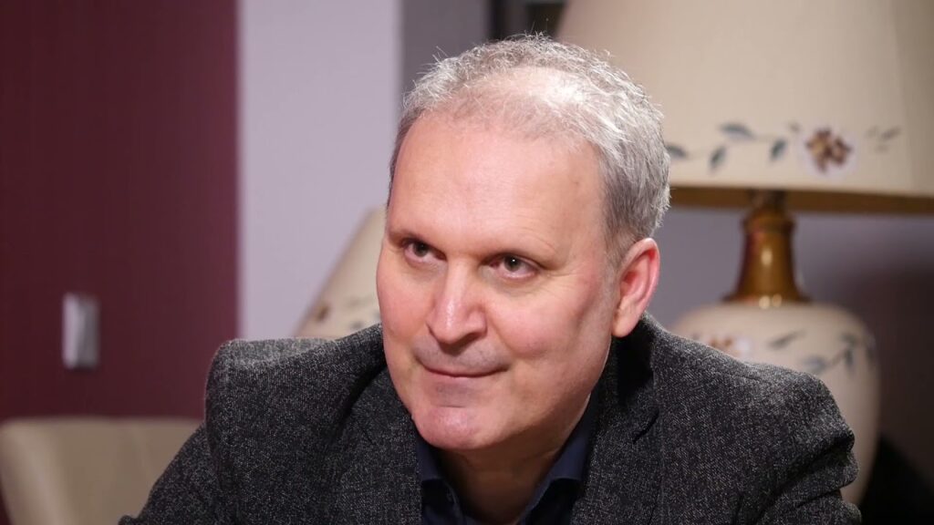 a man sitting in a chair with a lamp in the background
