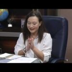A woman sitting at a desk with her hands together