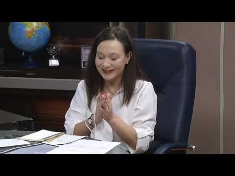 A woman sitting at a desk with her hands together
